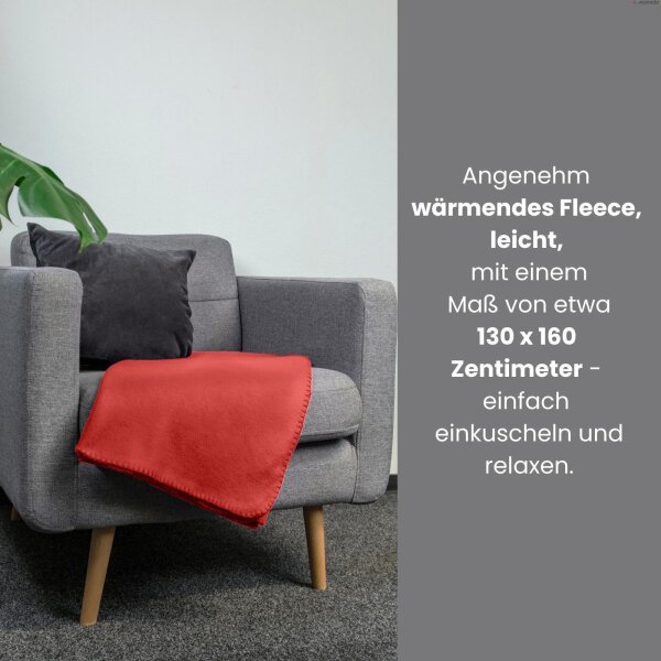 Eine leuchtend rote Fleecedecke liegt auf einem grauen Sessel und lädt zum Einkuscheln und Relaxen ein.